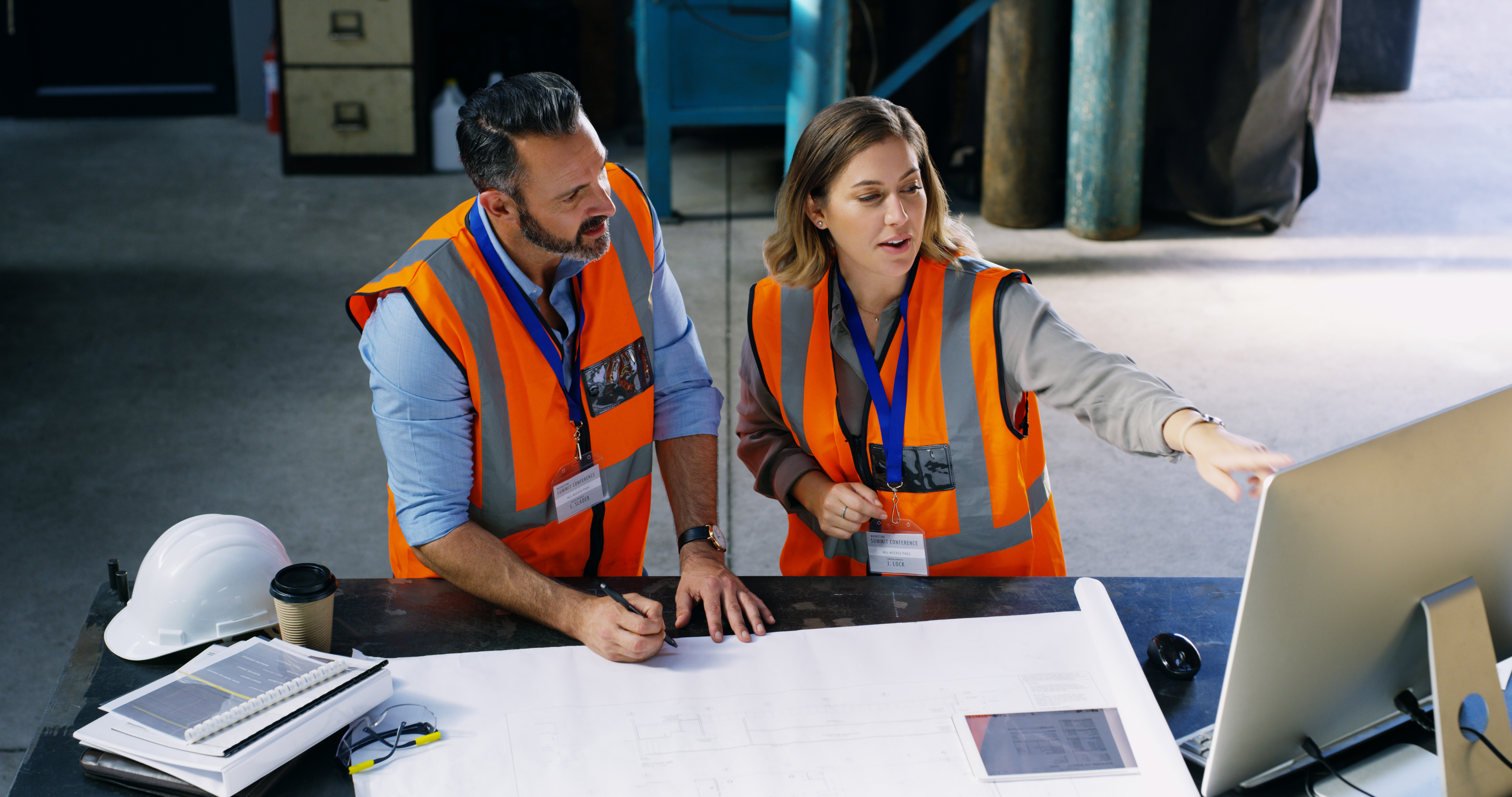 Shot of two engineers using a computer while going over a blueprint in an industrial place of work